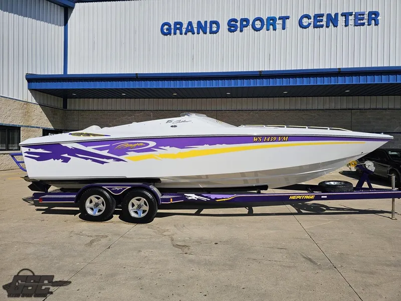 Slide: The Image of 2004 Baja 25 Outlaw speedboat with vibrant purple and yellow graphics on a trailer. - 4