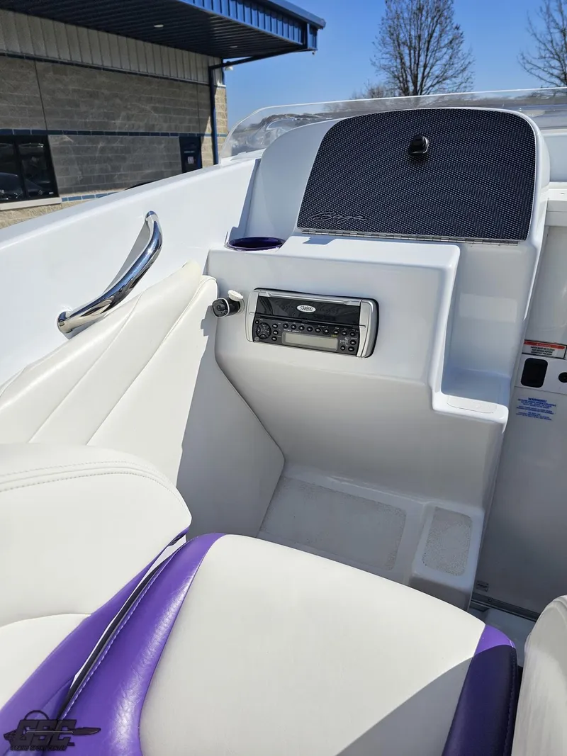 Slide: The Image of 2004 Baja 25 Outlaw boat interior with white and purple seating, stereo system, and sleek design. - 49