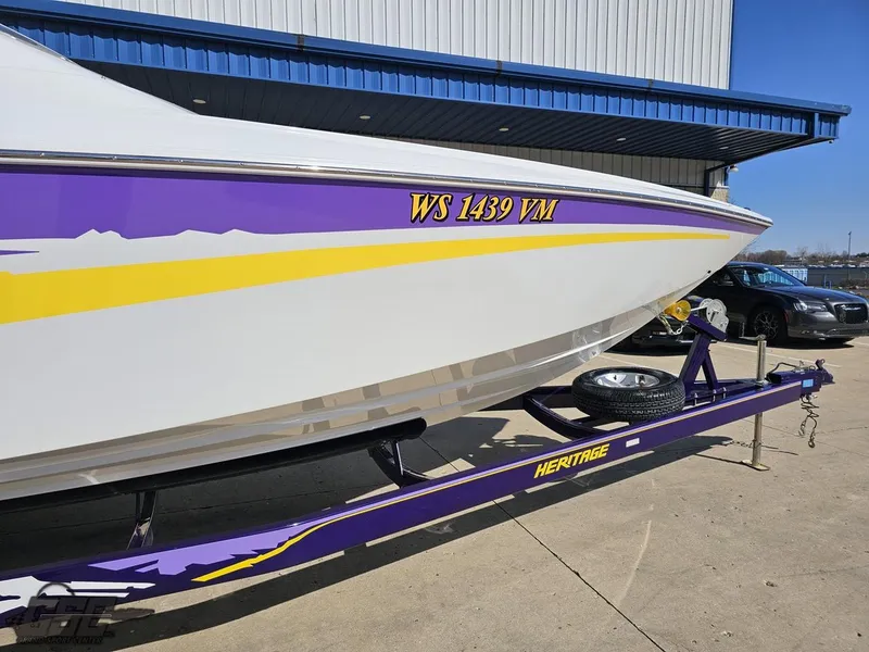 Slide: The Image of 2004 Baja 25 Outlaw boat on a purple Heritage trailer, parked outdoors. - 6