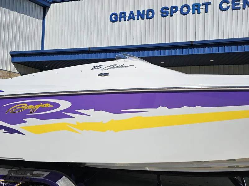 Slide: The Image of 2004 Baja 25 Outlaw boat with vibrant purple and yellow graphics at Grand Sport Center. - 7