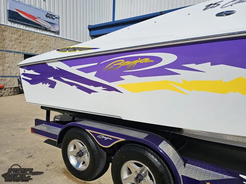 Slide: The Image of 2004 Baja 25 Outlaw boat with vibrant purple and yellow graphics on a trailer. - 8