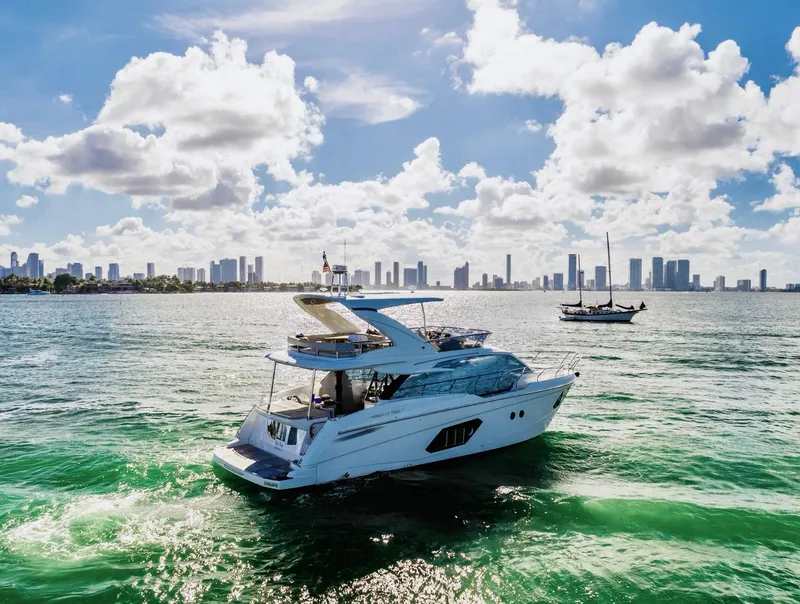 Slide: The Image of Luxury yacht Absolute 52 FLY 2018 cruising on vibrant waters with city skyline backdrop. - 3