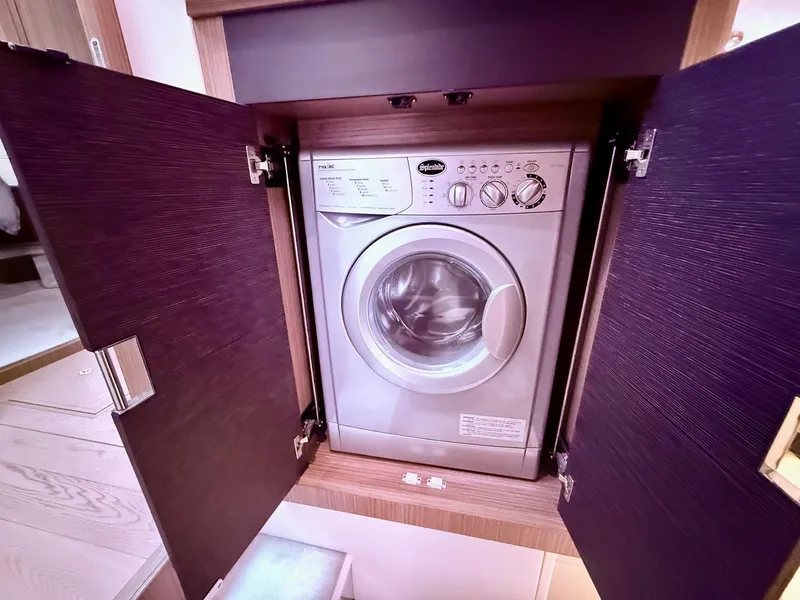 Slide: The Image of Washing machine inside Absolute 52 FLY yacht, 2018 model, with open wooden cabinet doors. - 39