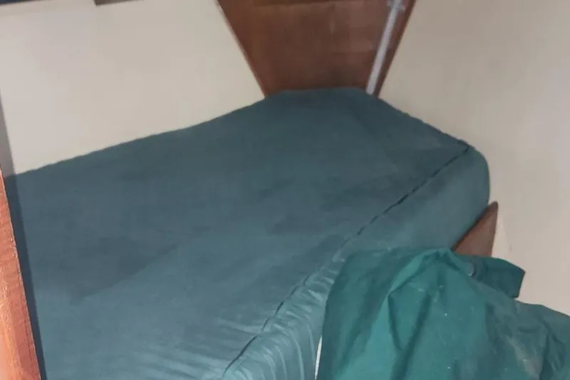 Slide: The Image of Interior cabin of 1984 Clearwater Cutter with a green bed and wooden paneling. - 14