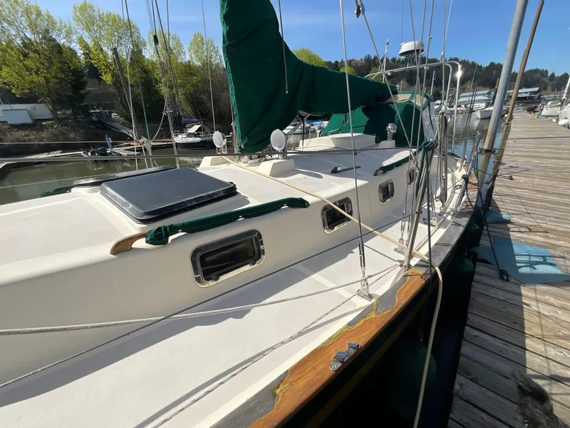 Slide: The Image of 1984 Clearwater Cutter sailboat docked, featuring green sails and a wooden deck. - 16