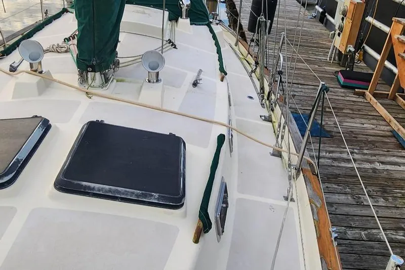 Slide: The Image of 1984 Clearwater CUTTER sailboat docked, featuring deck details and green sail covers. - 18