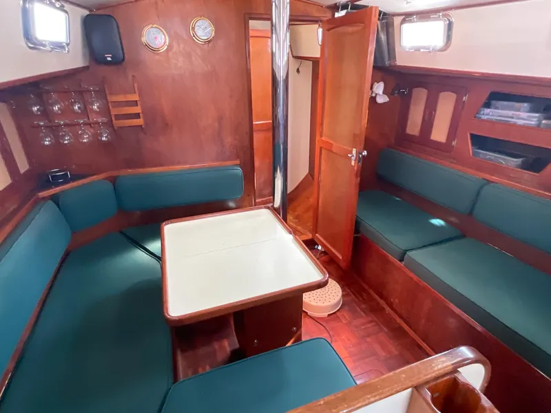 Slide: The Image of 1984 Clearwater Cutter sailboat interior with wooden finish and green seating. - 3