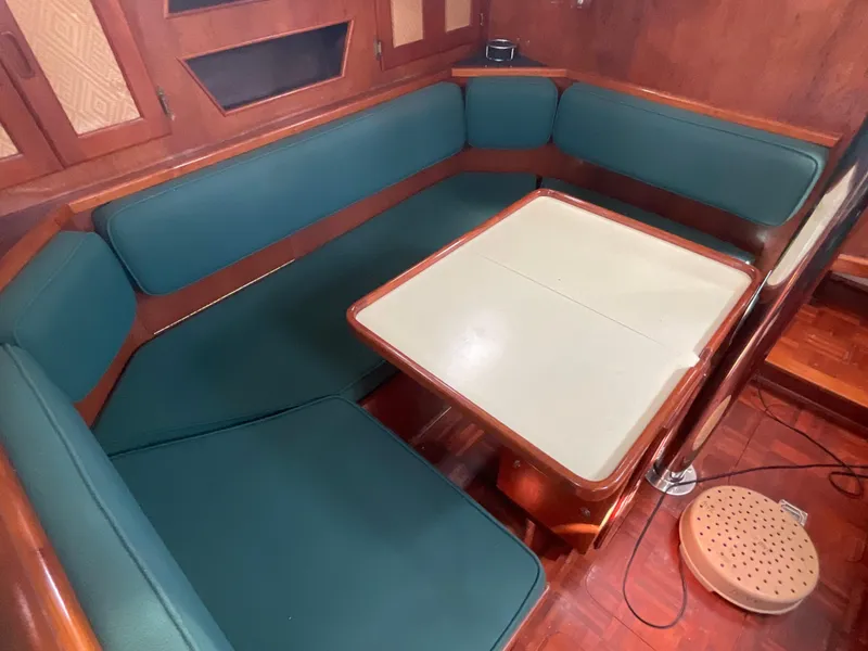 Slide: The Image of 1984 Clearwater CUTTER interior with green cushioned seating and foldable table. - 6