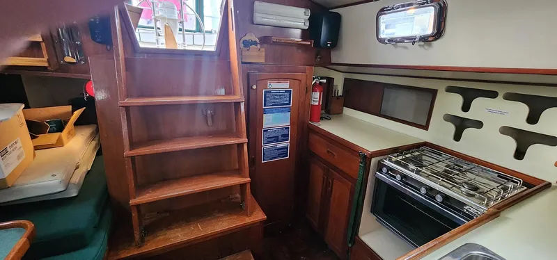 Slide: The Image of 1984 Clearwater Cutter interior with wooden stairs, compact kitchen, and storage cabinets. - 9