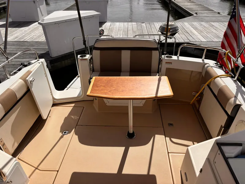 Slide: The Image of 2016 Cutwater 28 LE boat interior with seating and wooden table, docked at marina. - 15