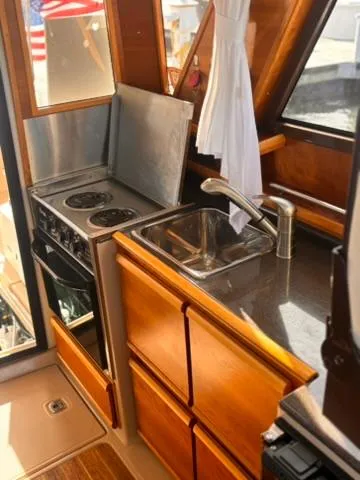 Slide: The Image of 2016 Cutwater 28 LE boat kitchen with stove, sink, and wooden cabinetry. - 18