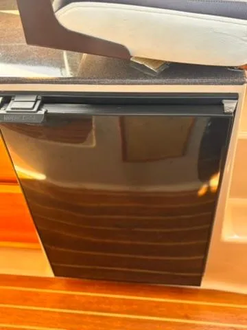 Slide: The Image of 2016 Cutwater 28 LE interior with sleek black refrigerator and wooden flooring. - 19