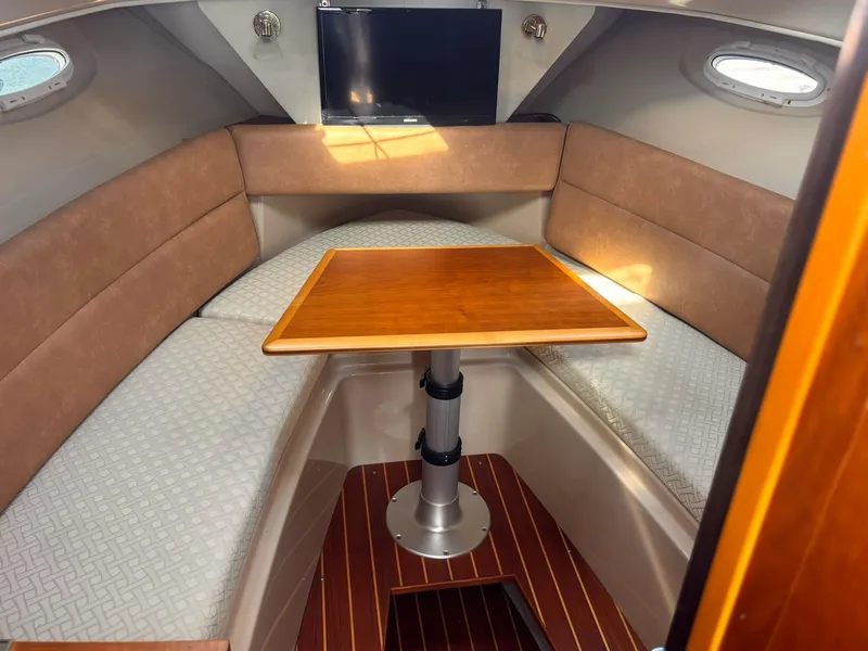 Slide: The Image of 2016 Cutwater 28 LE cabin interior with wood table, cushioned seating, and mounted TV. - 23
