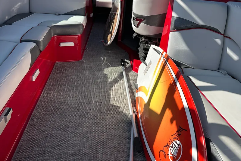 Slide: The Image of Interior of 2015 Supra SG400-550 boat with red and gray seating, surfboard, and carpeted floor. - 19