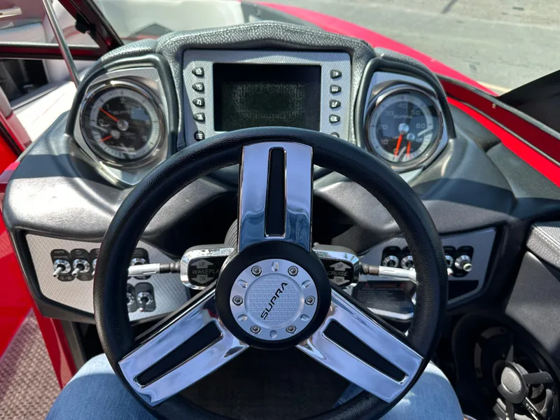 Slide: The Image of Steering wheel and dashboard of 2015 Supra SG400-550 boat, featuring modern gauges and controls. - 9