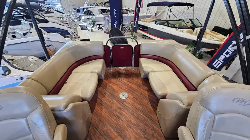 Slide: The Image of 2017 Manitou 25 Aurora LE pontoon boat interior with beige seating and wood flooring. - 11