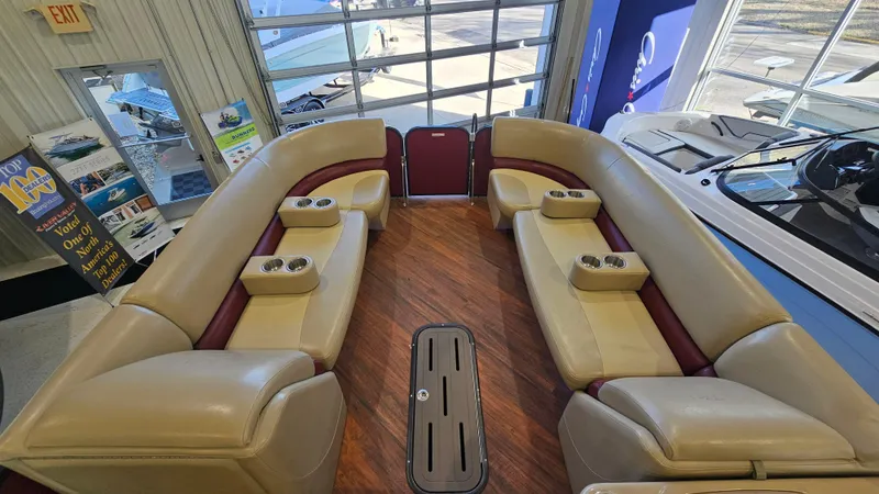 Slide: The Image of 2017 Manitou 25 Aurora LE pontoon boat interior with beige seating and cup holders. - 13