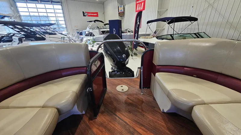 Slide: The Image of 2017 Manitou 25 Aurora LE pontoon boat interior with beige seating in showroom. - 33