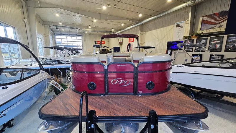 Slide: The Image of 2017 Manitou 25 Aurora LE pontoon boat displayed in a showroom with other boats. - 5