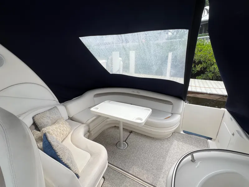 Slide: The Image of 2005 Sea Ray 340 Sundancer interior with cushioned seating and table under canopy. - 10