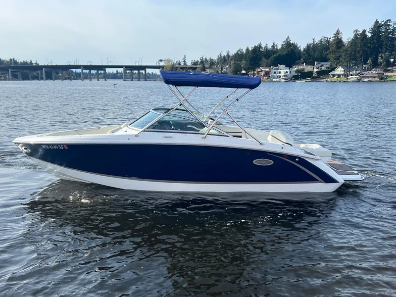 Slide: The Image of 2015 Cobalt R3 boat with blue hull on a calm lake, bridge and trees in background. - 1