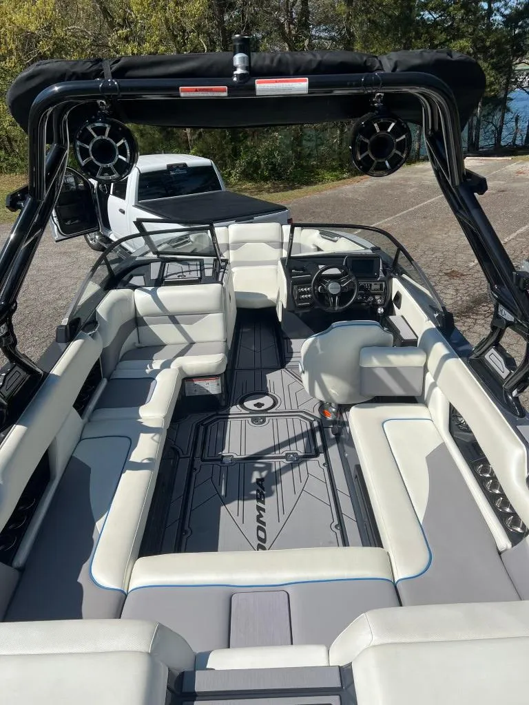 Slide: The Image of 2022 Moomba Mojo boat interior with seating and steering wheel, parked near a lake. - 10