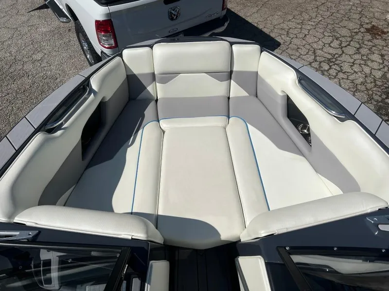 Slide: The Image of 2022 Moomba Mojo boat interior with white and gray seating, parked on pavement. - 11