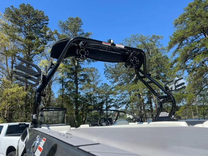 Slide: The Image of 2022 Moomba Mojo boat with wakeboard tower, set against a clear blue sky and trees. - 19