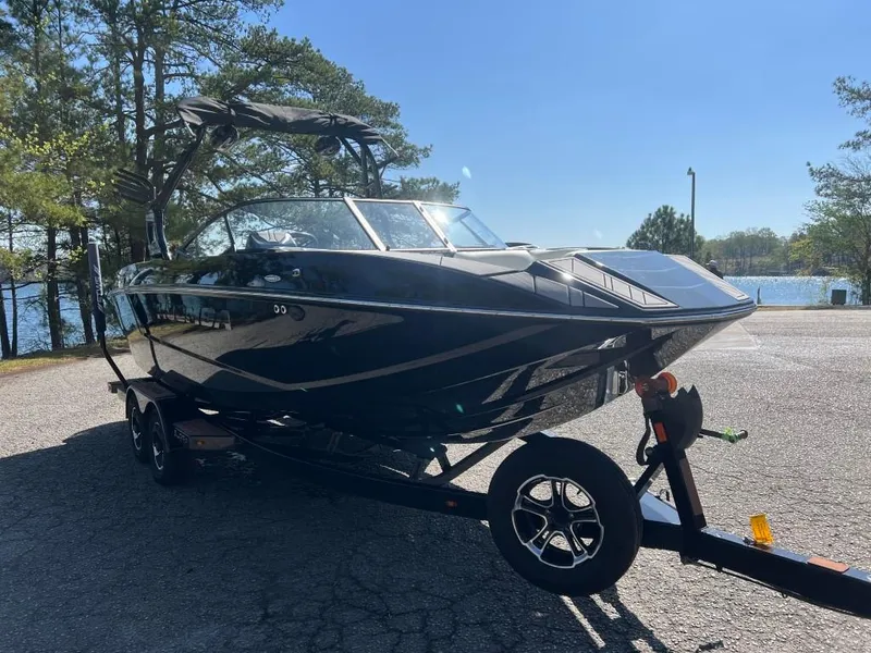 Slide: The Image of 2022 Moomba Mojo boat on trailer, parked near a lake with trees in the background. - 3