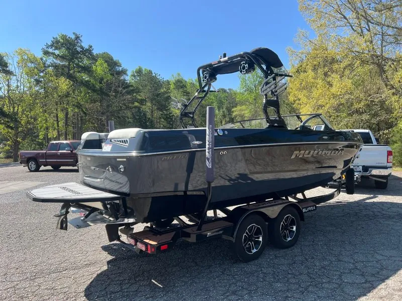 Slide: The Image of 2022 Moomba Mojo boat on trailer, parked outdoors with trees in the background. - 5