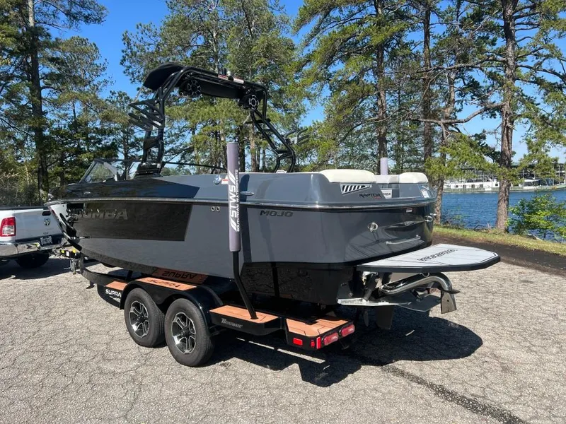 Slide: The Image of 2022 Moomba Mojo boat on trailer near lake, surrounded by trees. - 8