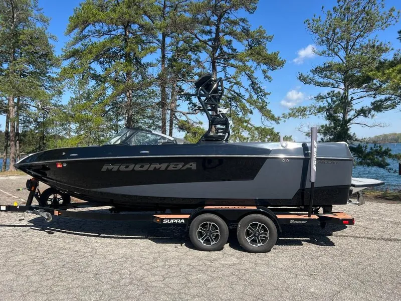 Slide: The Image of 2022 Moomba Mojo boat on trailer, parked near a lake with trees in the background. - 9