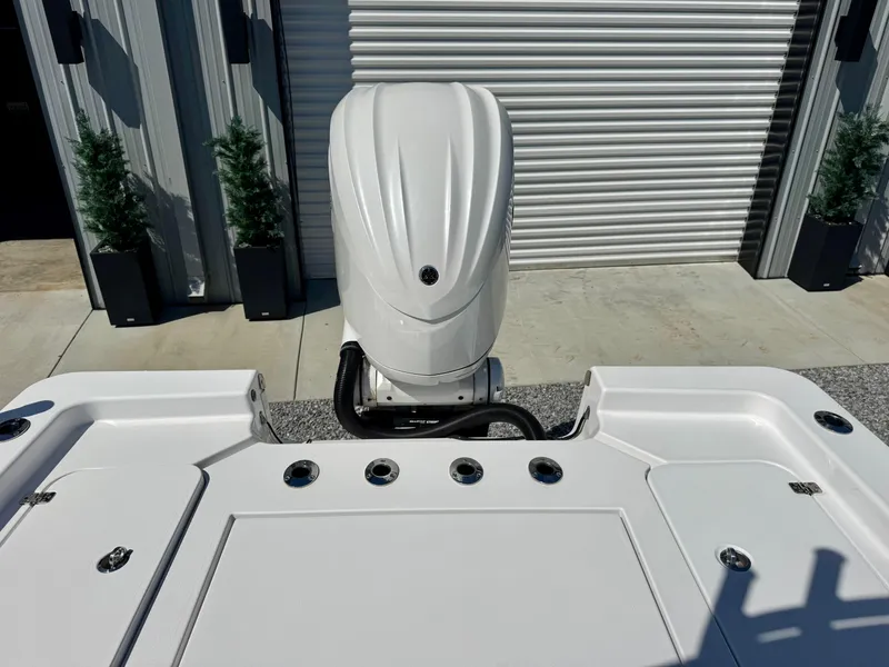 Slide: The Image of 2022 Sportsman 247OE boat with outboard motor, docked near a metal building. - 10