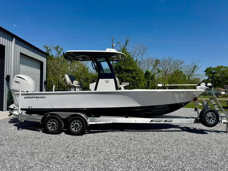 Slide: The Image of 2022 Sportsman 247OE boat on trailer, parked outdoors under clear blue sky. - 2