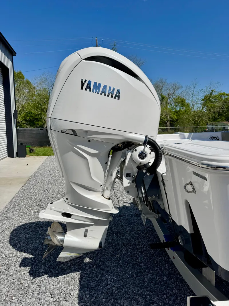 Slide: The Image of 2022 Sportsman 247OE boat with Yamaha outboard motor, parked on gravel under clear blue sky. - 4