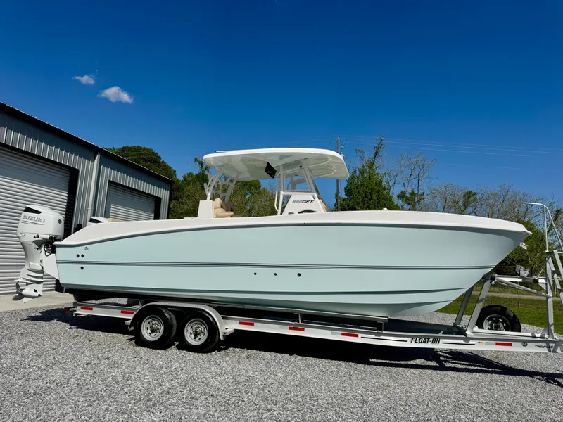 Slide: The Image of 2023 Twin Vee 280 GFX CC boat on trailer, parked outdoors under clear blue sky. - 17