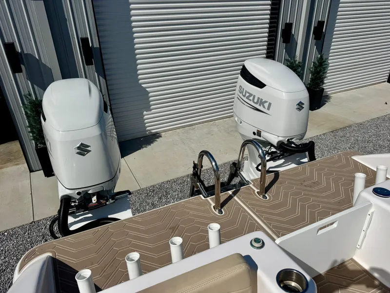 Slide: The Image of 2023 Twin Vee 280 GFX CC boat with dual Suzuki outboard motors, docked near storage units. - 29