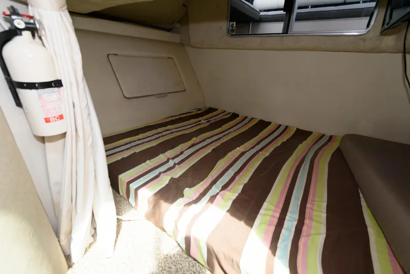 Slide: The Image of 1996 Maxum 2700 SCR cabin interior with striped bedding and fire extinguisher. - 10