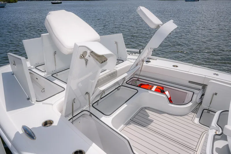 Slide: The Image of 2024 Freeman 28 boat deck with open storage compartments and seating, on calm water. - 15