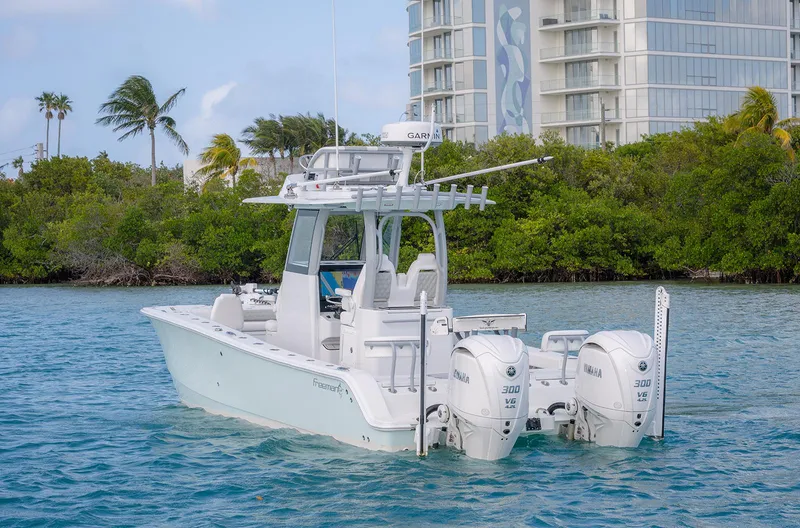 Slide: The Image of 2024 Freeman 28 boat with dual engines on blue water near a modern building. - 2