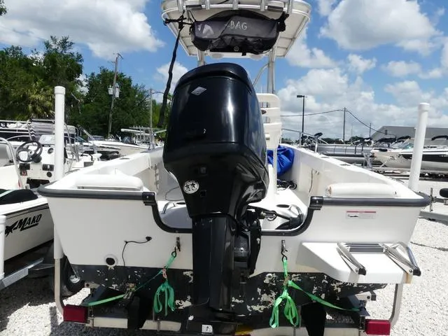 Slide: The Image of 2006 Boston Whaler 190 Outrage boat with outboard motor, parked outdoors under a cloudy sky. - 5