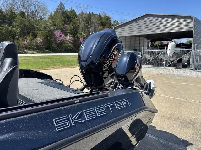 Slide: The Image of 2024 Skeeter WXR2060 F boat with powerful outboard motor, parked near a storage facility. - 12