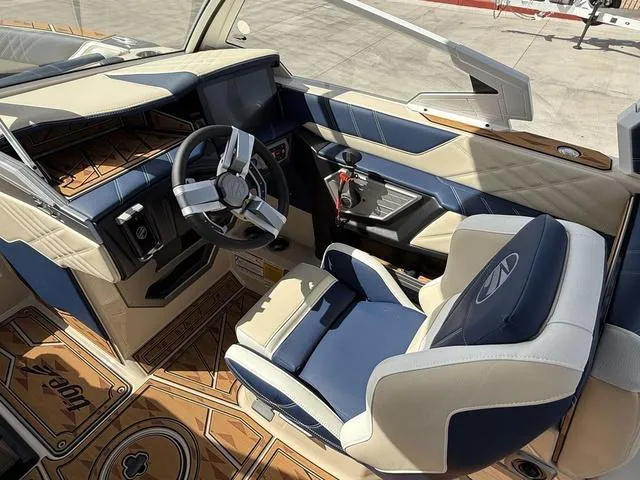 Slide: The Image of 2025 Tigé 23ZX boat interior with blue and beige seating, modern dashboard, and stylish steering wheel. - 12