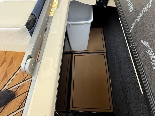 Slide: The Image of 2025 Tigé 23ZX boat interior storage compartment with trash bin and wooden flooring. - 16
