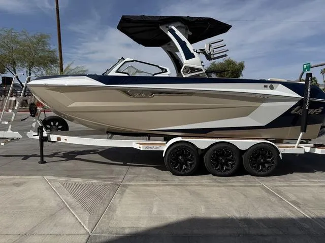 Slide: The Image of 2025 Tigé 23ZX boat on trailer, sleek design, black canopy, parked outdoors. - 5
