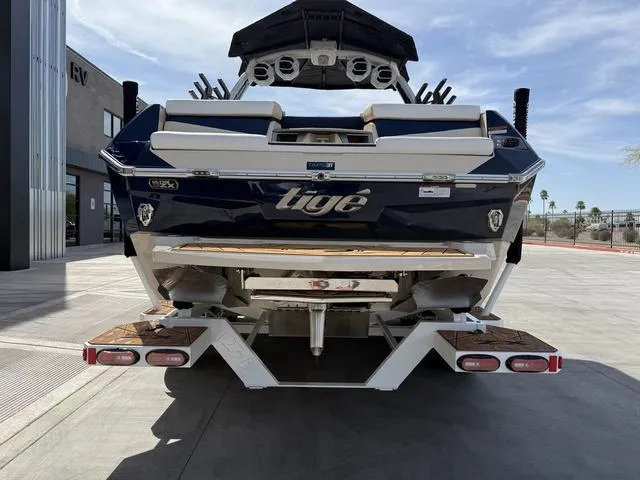 Slide: The Image of 2025 Tigé 23ZX boat rear view, parked outdoors on a sunny day. - 7