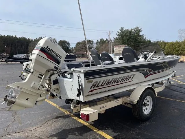 Slide: The Image of 1998 Alumacraft PRO 195 boat with Johnson outboard motor on a trailer in a parking lot. - 6