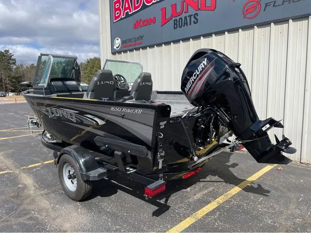 Slide: The Image of 2016 Lund 1650 Rebel XL Sport boat with Mercury outboard motor, parked outside dealership. - 6