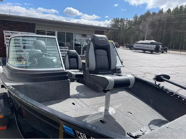 Slide: The Image of 2016 Lund 1650 Rebel XL Sport boat with seating, parked outdoors under a cloudy sky. - 9