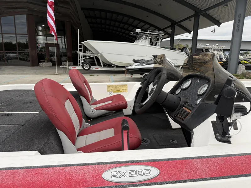 Slide: The Image of 2005 Skeeter SX 200 boat interior with red seats and dashboard, displayed outdoors. - 10